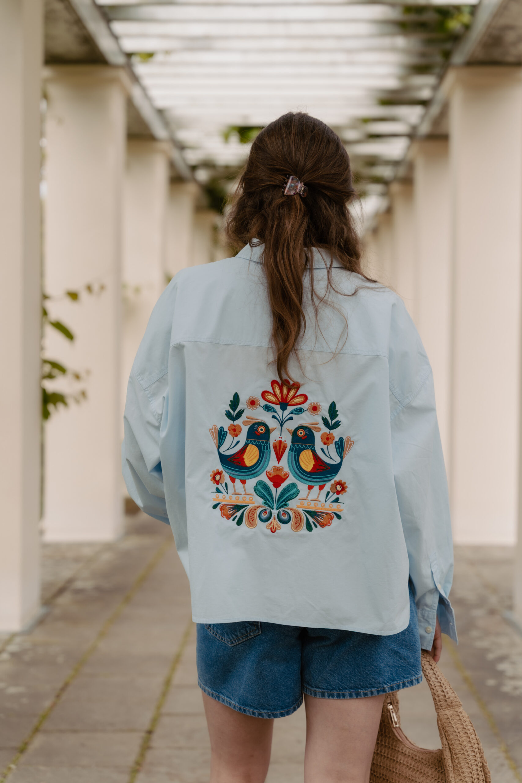 Hellblaues Overshirt mit farbig gesticktem Vogel- und Blumenmotiv auf dem Rücken