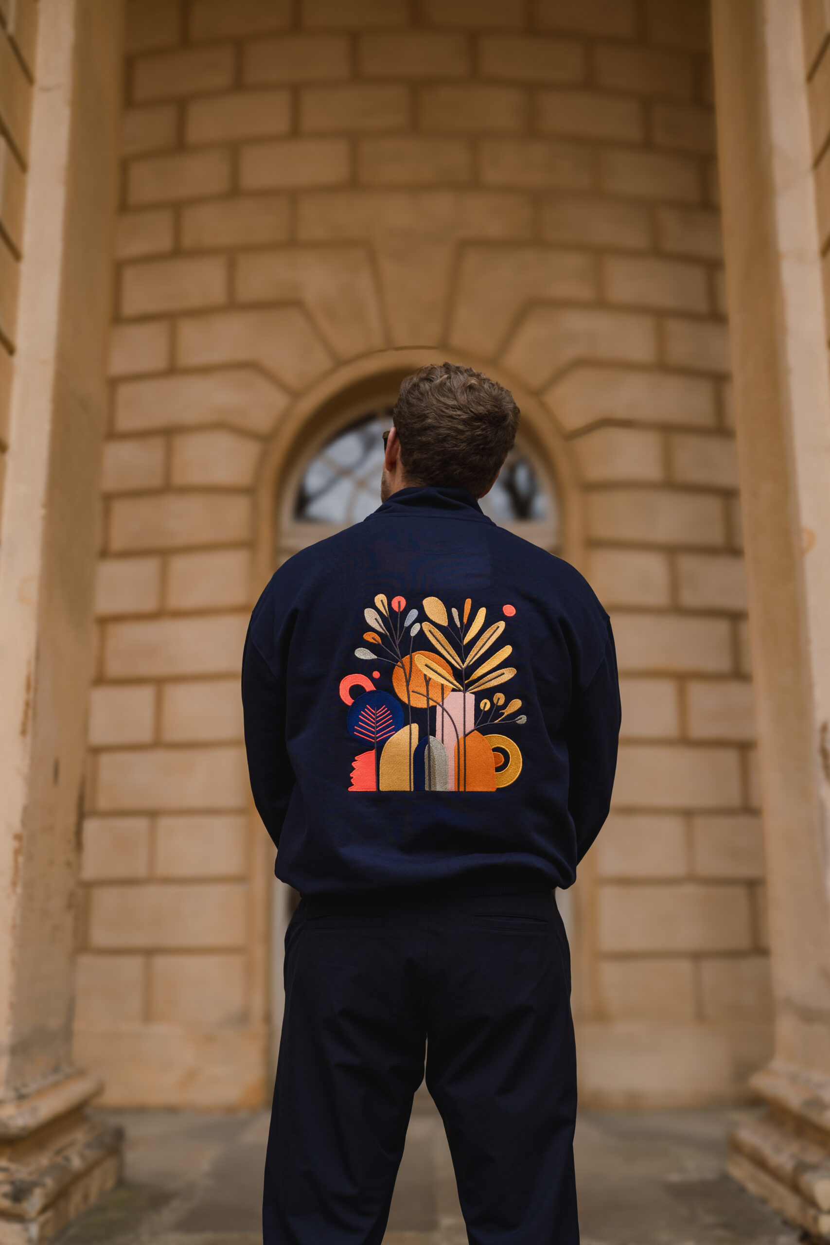 Dunkelblaues Sweatshirt mit farbigem floralen und geometrischen Stickmotiv auf dem Rücken